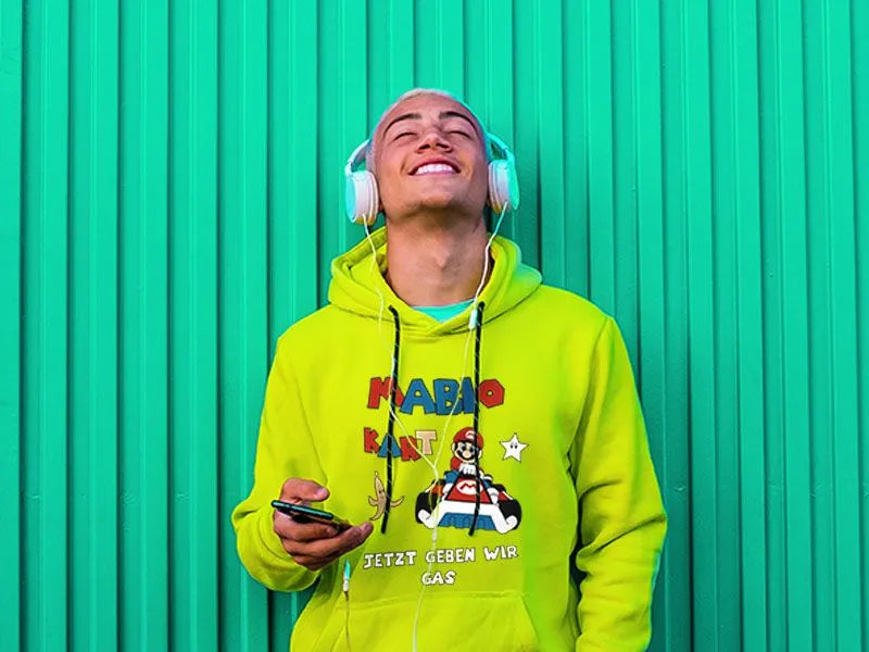 Junger Mann im neongelben Hoodie mit Mario-Kart-Abimotiv-Druck